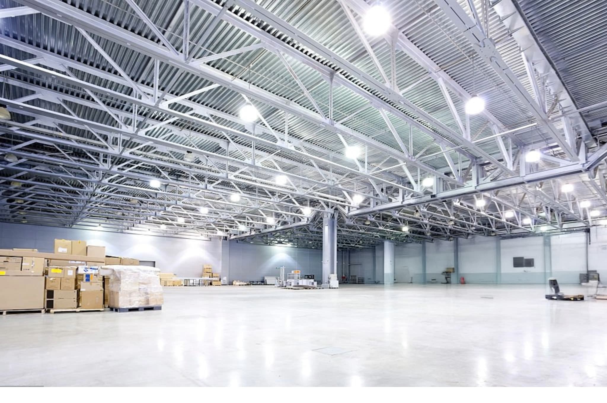 Illuminated LED high-bay lighting across a steel roof structure in a large industrial warehouse